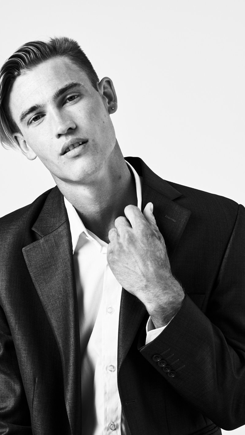 black and white image of white male model in formal suit with shirt unbuttoned at the neck 