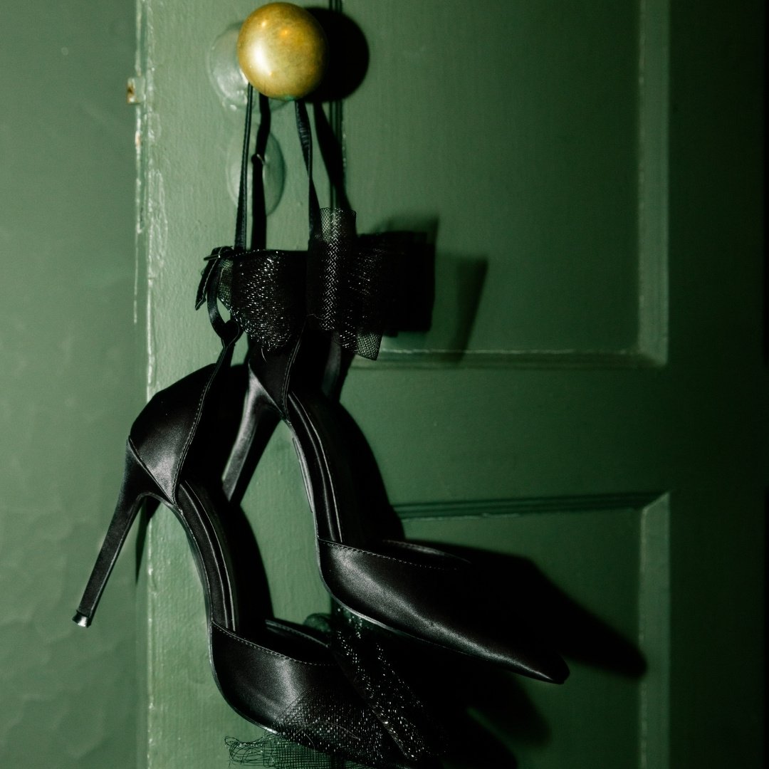 black heels hanging off a door knob on a green door 