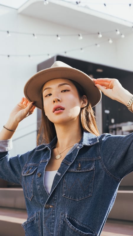 asian woman holding her har and wearing a denim jacket