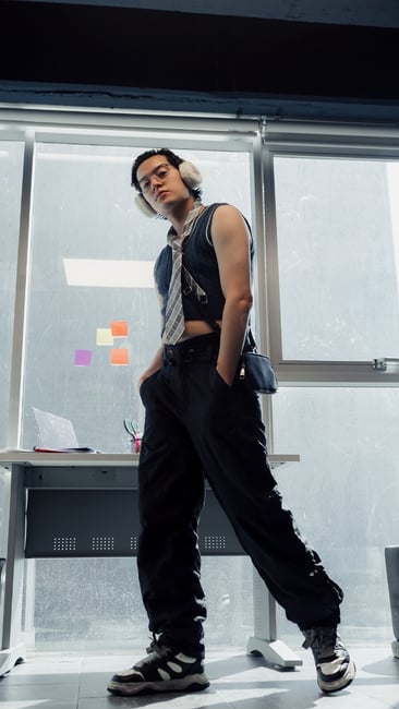 model in a cropped t shirt and tie standing in an office setting  