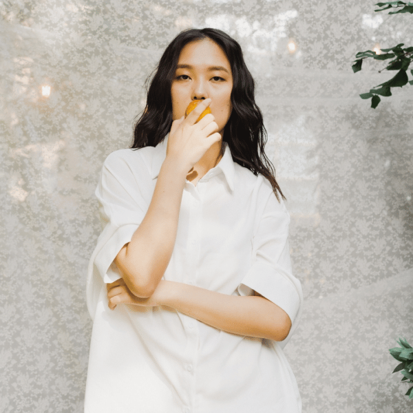 asian woman in a white shirt, biting an apple 