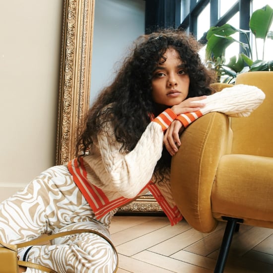 A woman with curly hair relaxes on a bright yellow couch, showcasing a cozy and inviting living space
