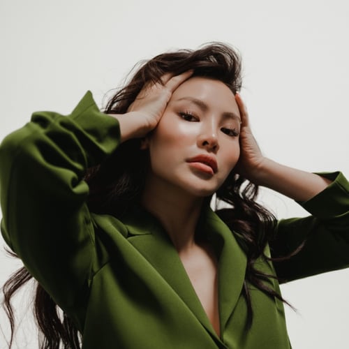 asian woman with two hands on her head, looking into the camera 