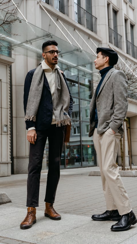two guys in business attire and scarves having a conversation outside a building 