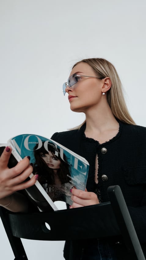 girl holding open a Vogue magazine, staring away from the camera 