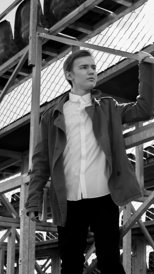 A man in a jacket stands on the bleachers, reaching upward with a focused expression