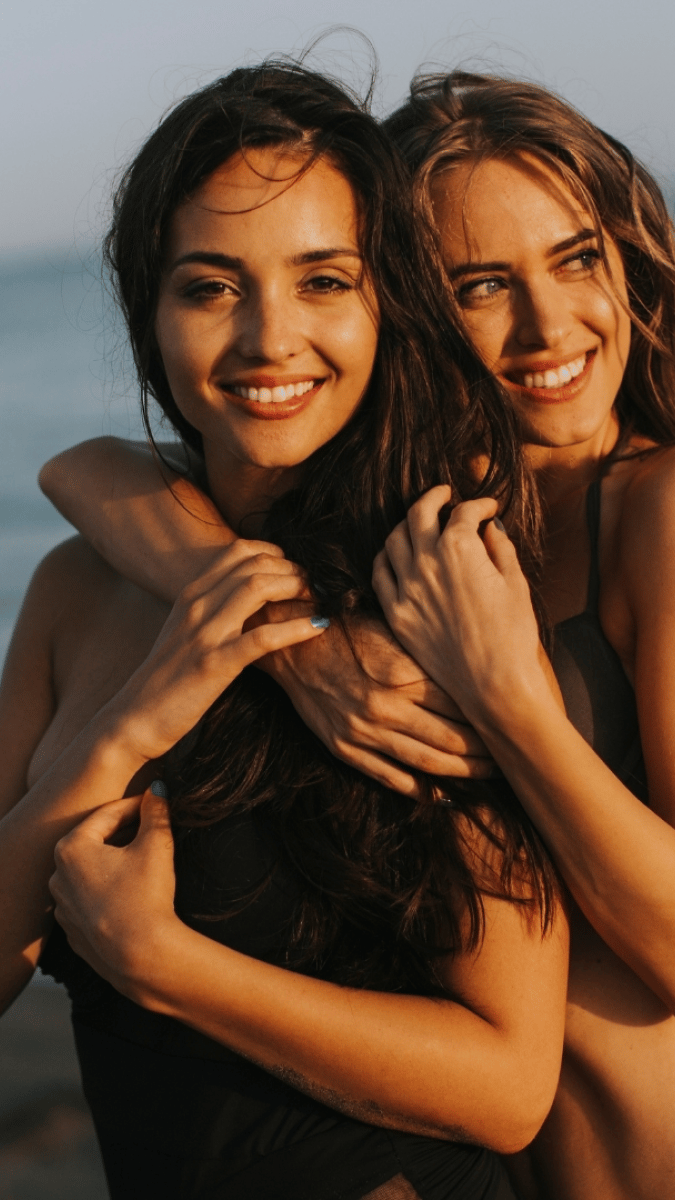 two girls, one with blonde hair holding the other over the shoulder 
