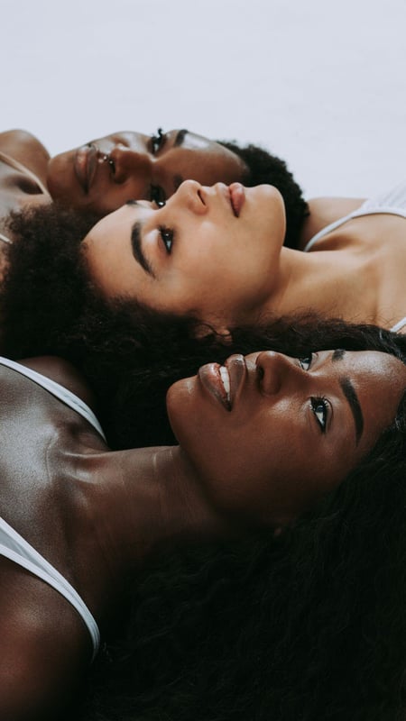 group of women, different faces, laying on the ground and staring upward