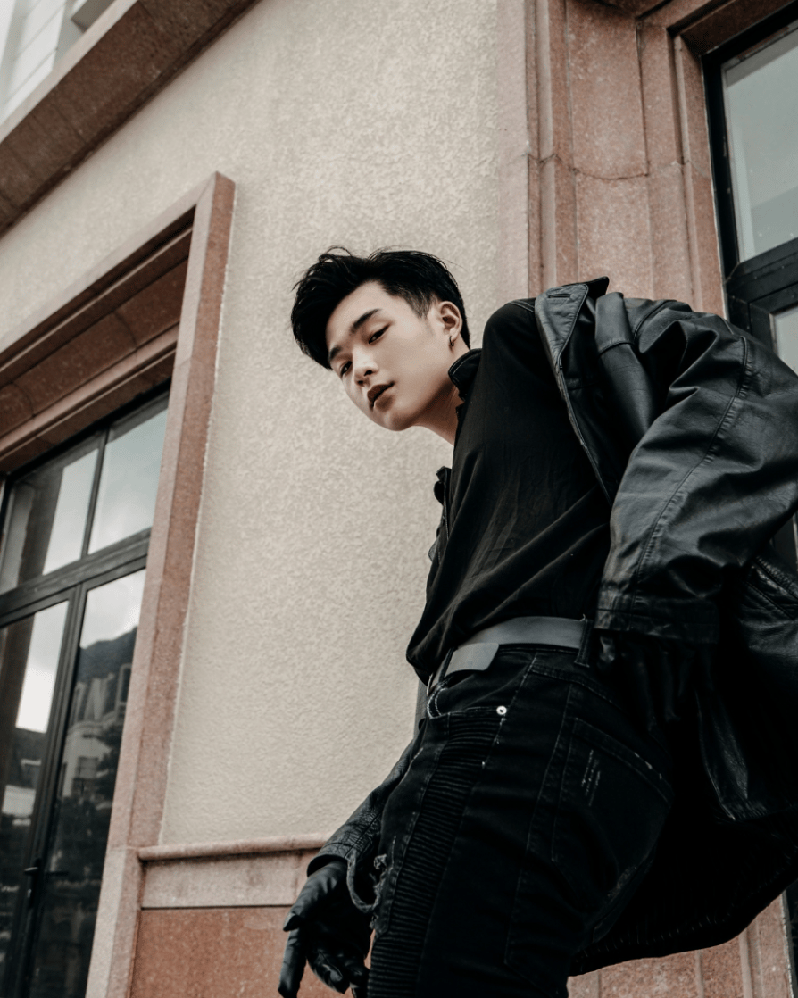 young guy in a leather jacket and black jeans, looking down into the camera 
