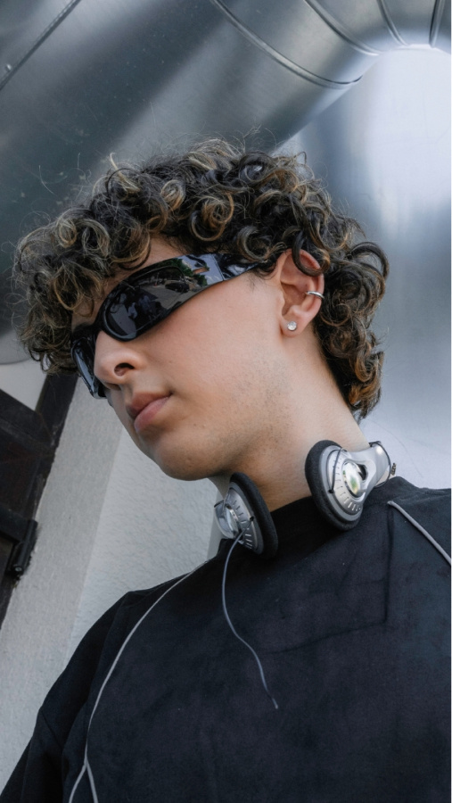 Boy with curly brown and blonde hair wearing thin, blackout sunglasses with walkman around his neck