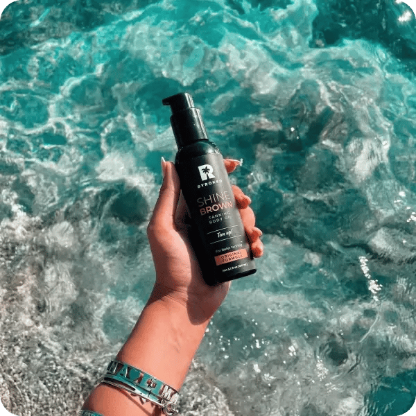 An influencer holding up a bottle of Byrokko product over the pool water