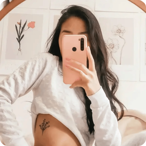 A rib tattoo of a flower bunch on a woman with long, dark brown hair