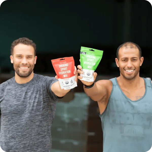 Two guys holding up a packet of Nooma hydration mix, smiling at the camera