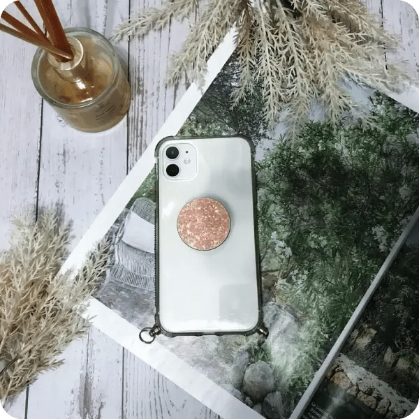 A clear phone case with a pink, glitter popsocket