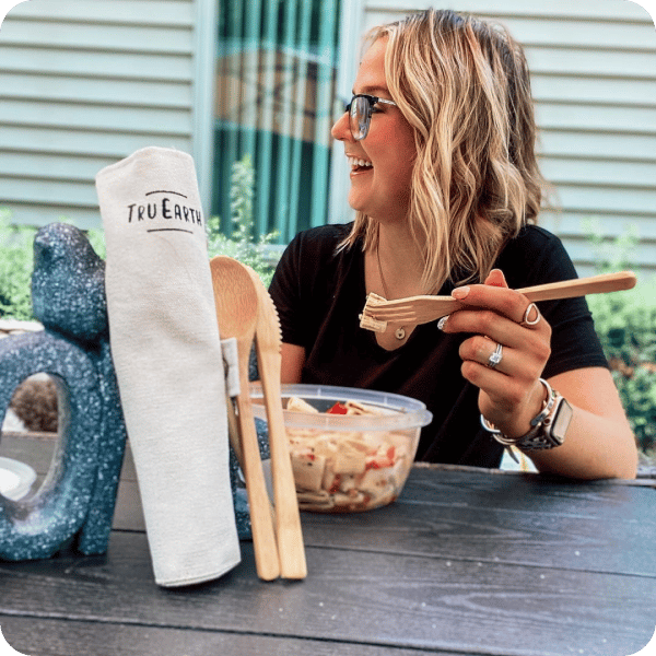 A woman wearing a salad, holding Tru Earth cutlery