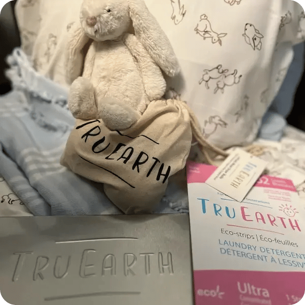 Tru Earth laundry detergent and linen bags accompanied by a stuffed bunny rabbit