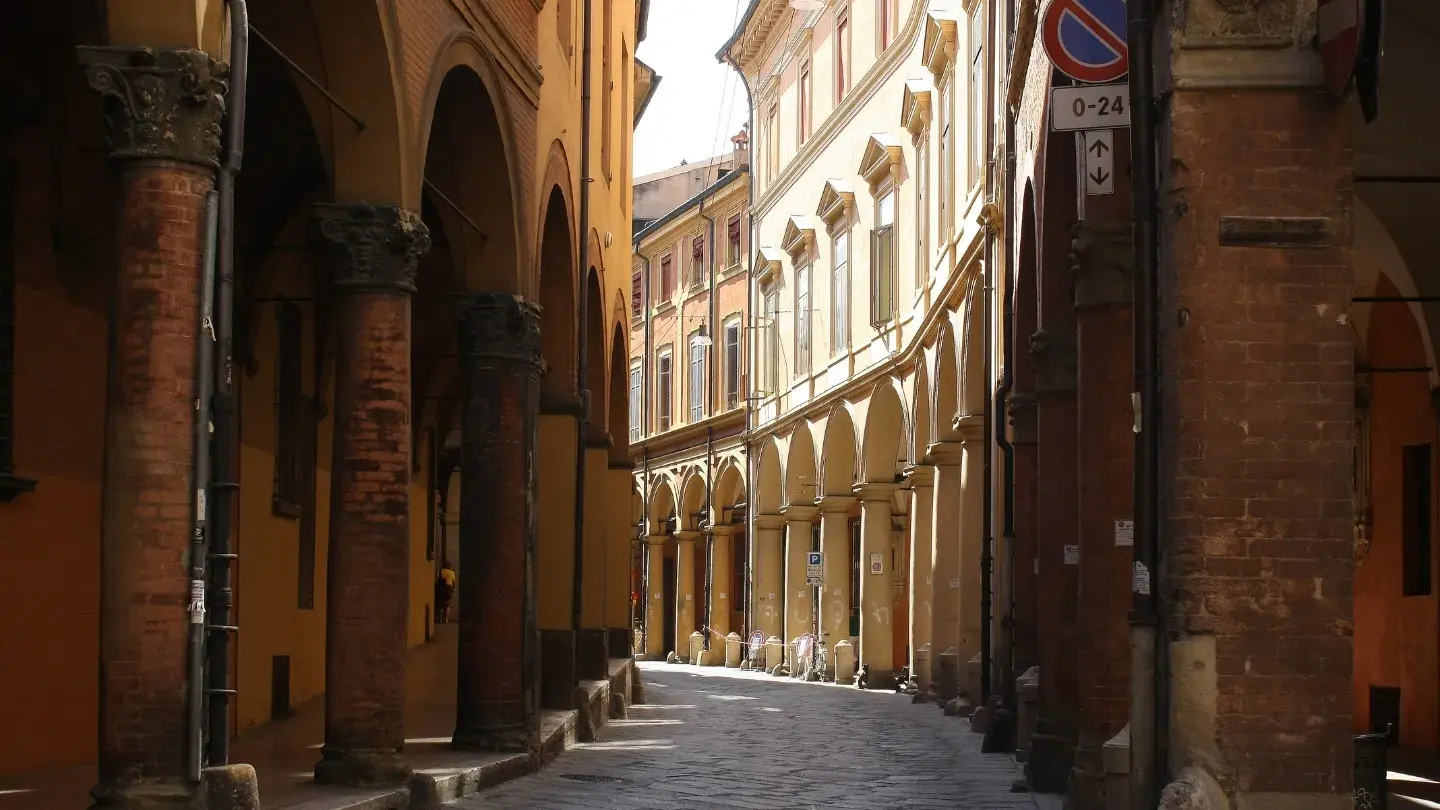 A narrow urban street lined with towering buildings and decorative pillars