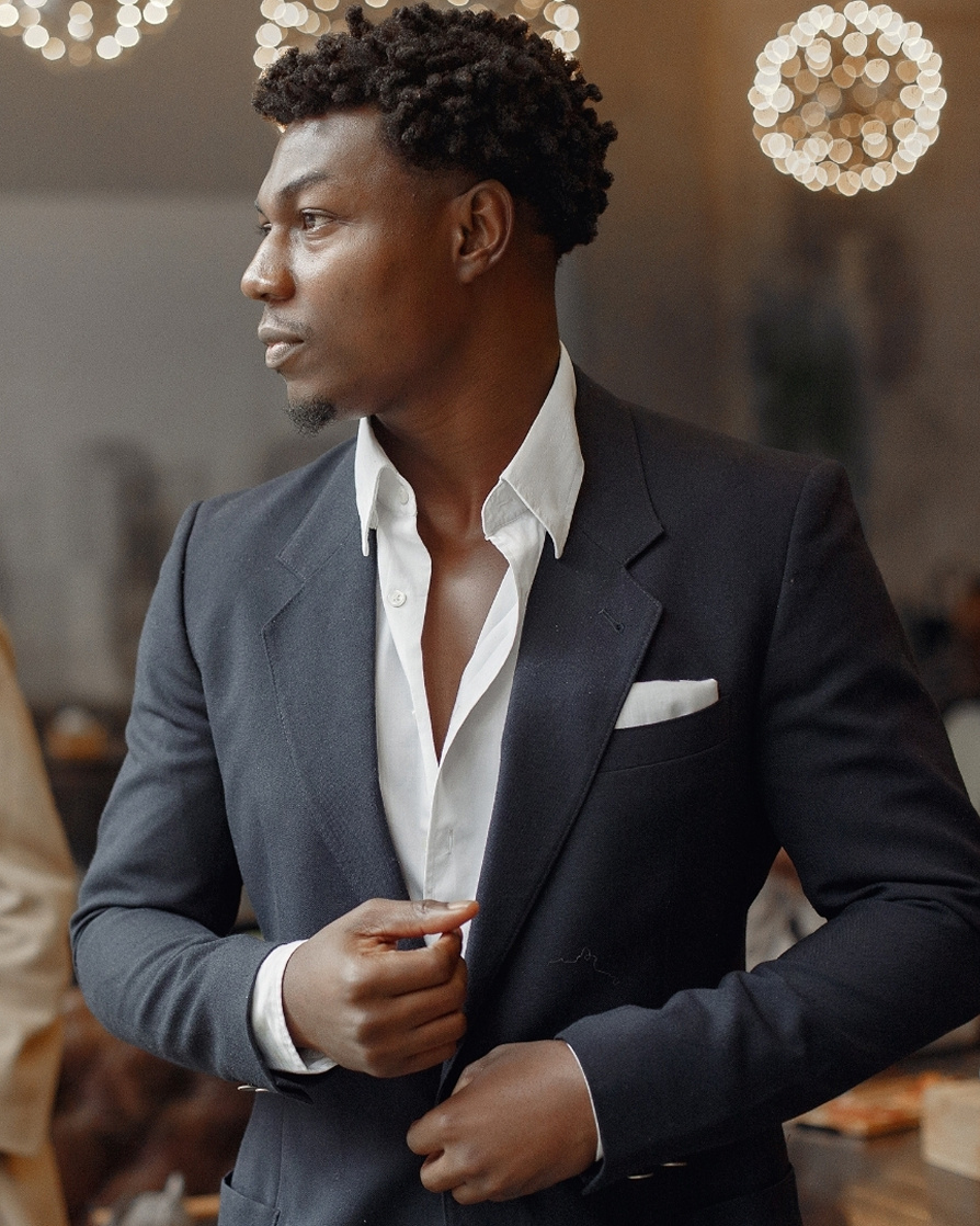 young guy in a suit with a shirt buttoned down slightly, looking away from the camera